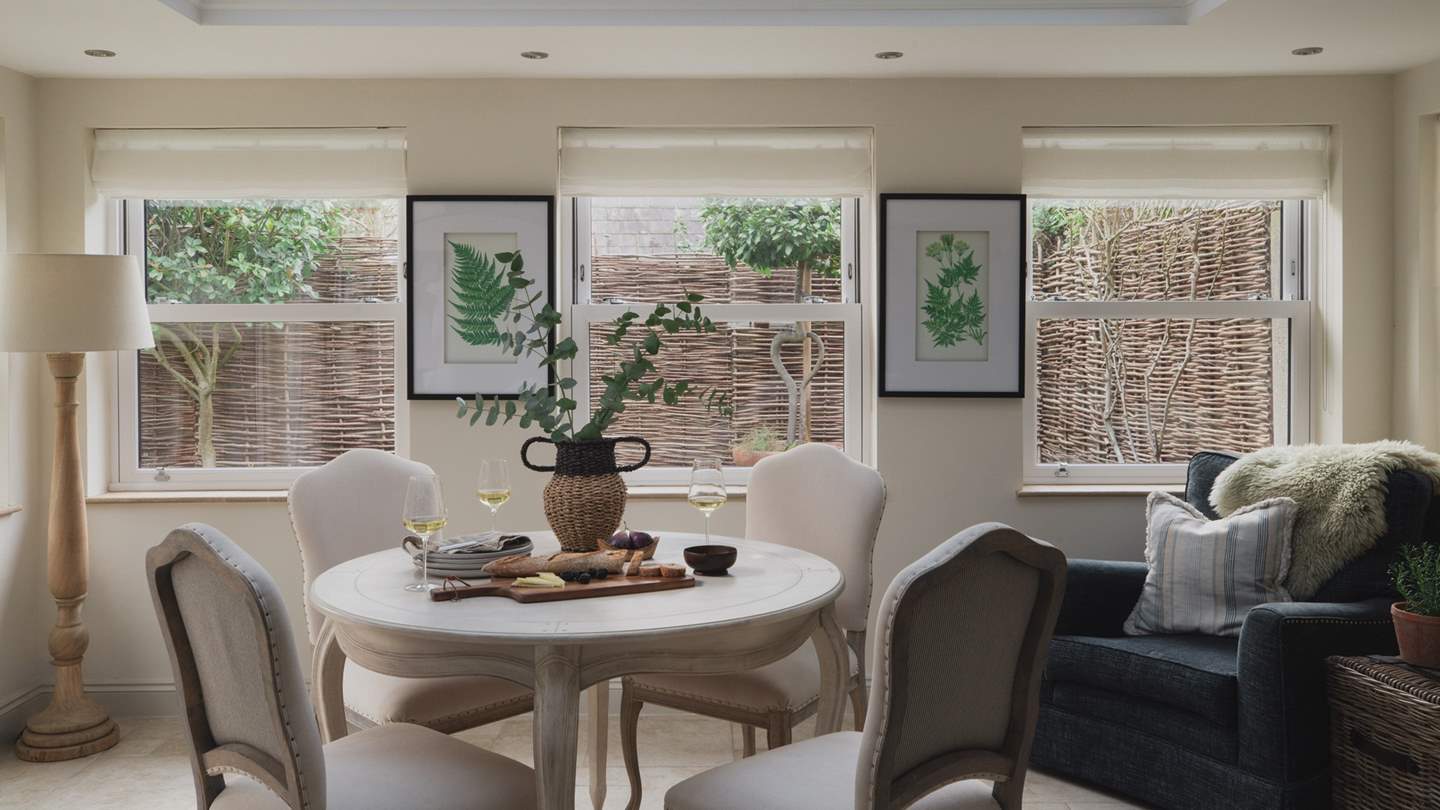 For dining, a chic table for four sits in the centre, with large windows overlooking the gorgeous verdant garden space