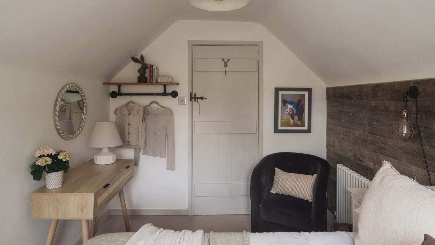 This space features two intricately detailed bedside tables, an oak dressing table with a upholstered stool, and a hanging rail for your belongings