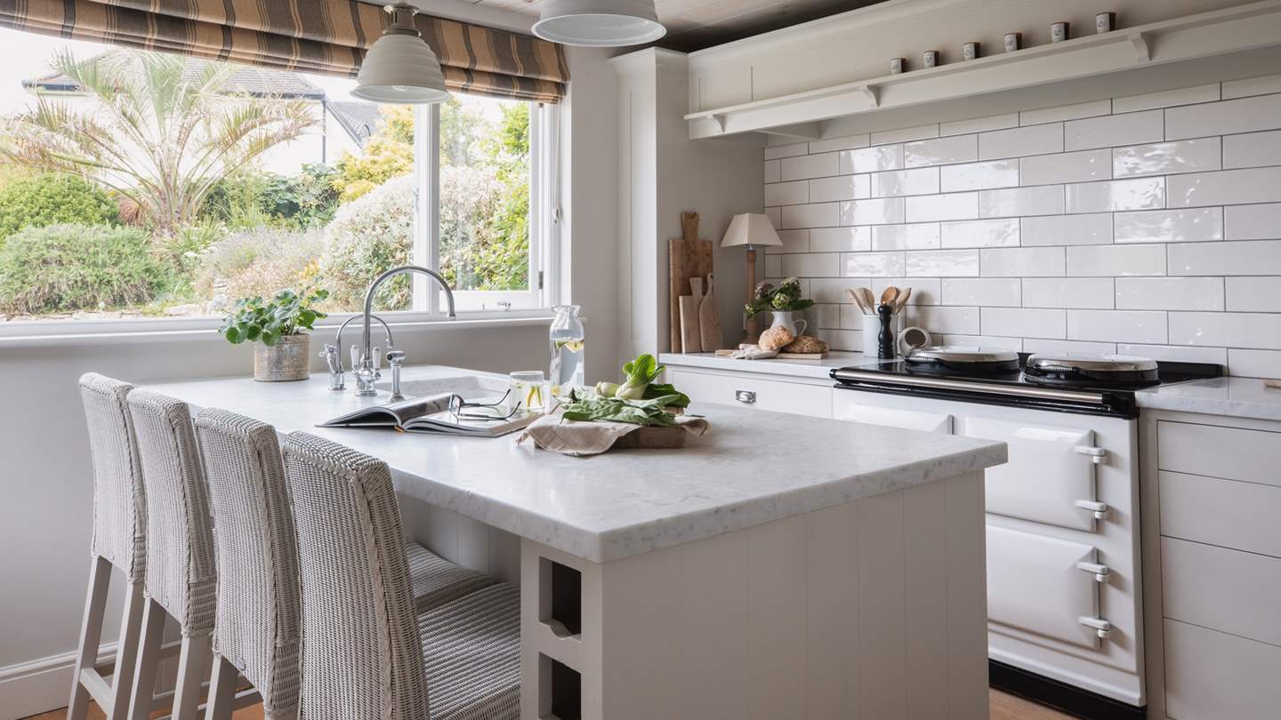 The kitchen at Polvarth, illuminated by a large garden-view window, has a sociable atmosphere with a peninsula offering plentiful meal preparation space 