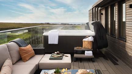 A bubbling hot tub resides on the balcony, with beautiful sea views in the distance