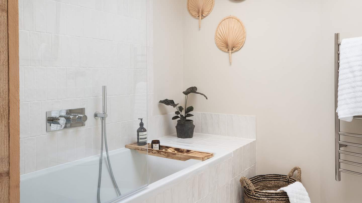 The ensuite, with iridescent ivory tiling and jute textiles has a tempting bathtub along with a showerhead