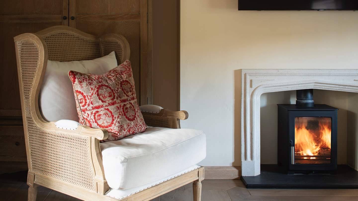 A charming occasional chair rests beside the wood burning stove, providing a lovely spot for moments of serene quietude...