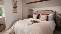 Gazing out onto the cottage garden, the divine master bedroom is dressed in soft cream tones