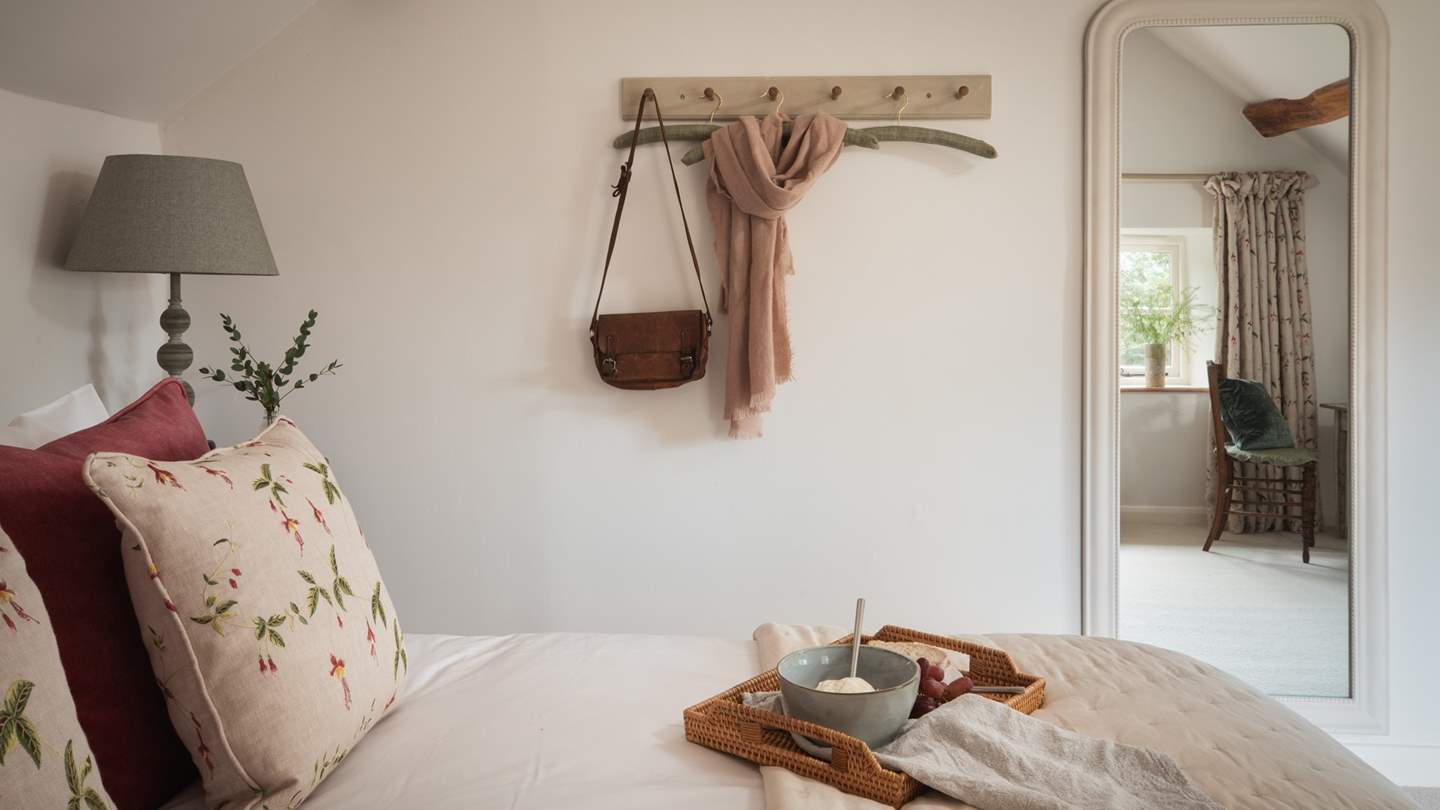 Boasting a sumptuous king-sized bed, two elegant wooden bedside tables, a full-length mirror, hanging space and an antique dressing table
