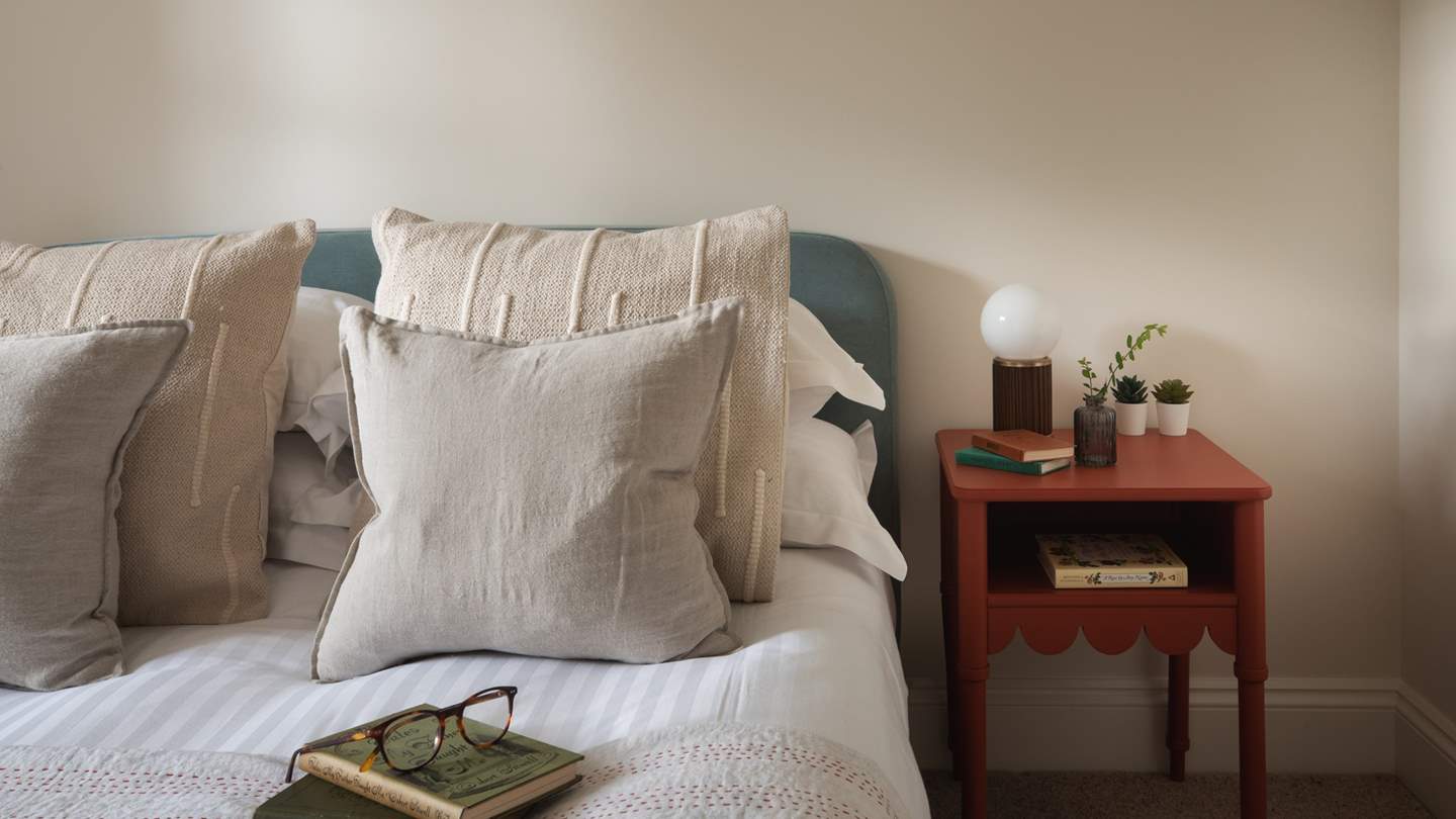 Plump pillows, cushions, and a beautiful floral quilt invite for a dreamy slumber or a cosy escape into your favourite book