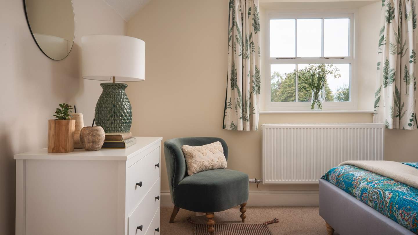 Wooden apples and pears adorn the polished chest of drawers while a stunning statement lamp lends its style and a soft glow to the room