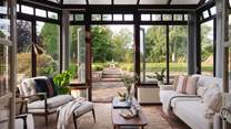Through a set of timeless French doors lies the bright and airy conservatory that enjoys sweeping views over the picture-perfect garden