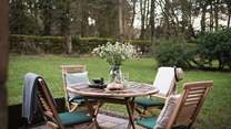 A teak garden table and chairs provide an enchanting setting for alfresco evening dining