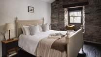 Overlooking The Barn, the calming third bedroom with a king-sized bed is set amidst stunning stone walls