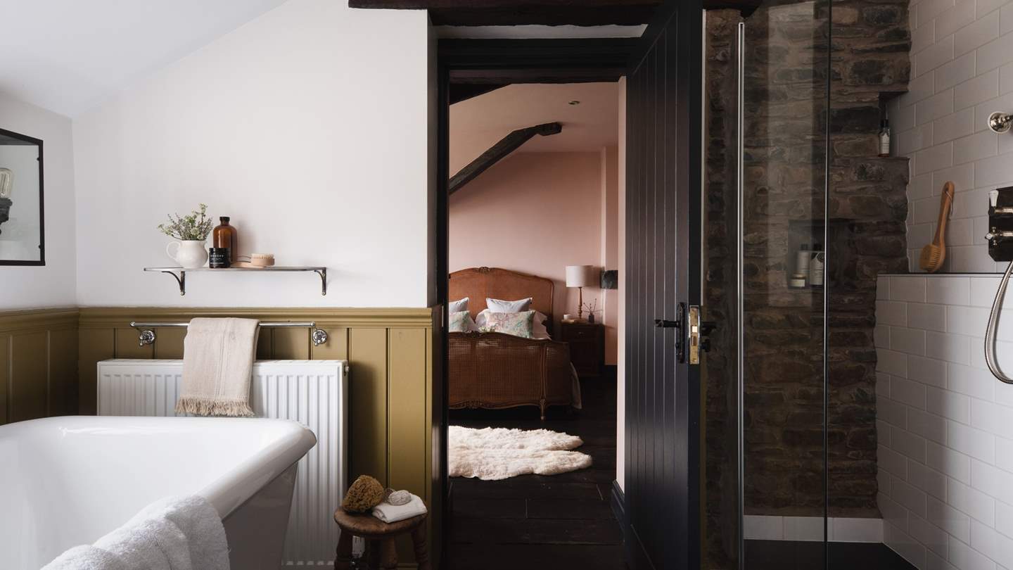 The heavenly en-suite with olive toned wood-panelling invites with both a beautiful walk-in shower and a freestanding bathtub for two