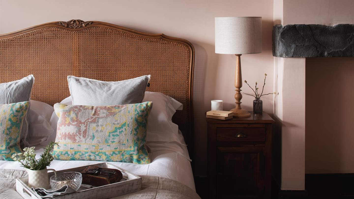 A French rattan king-sized bed topped with luxurious linens and plump pillows tempts for the sweetest of slumbers