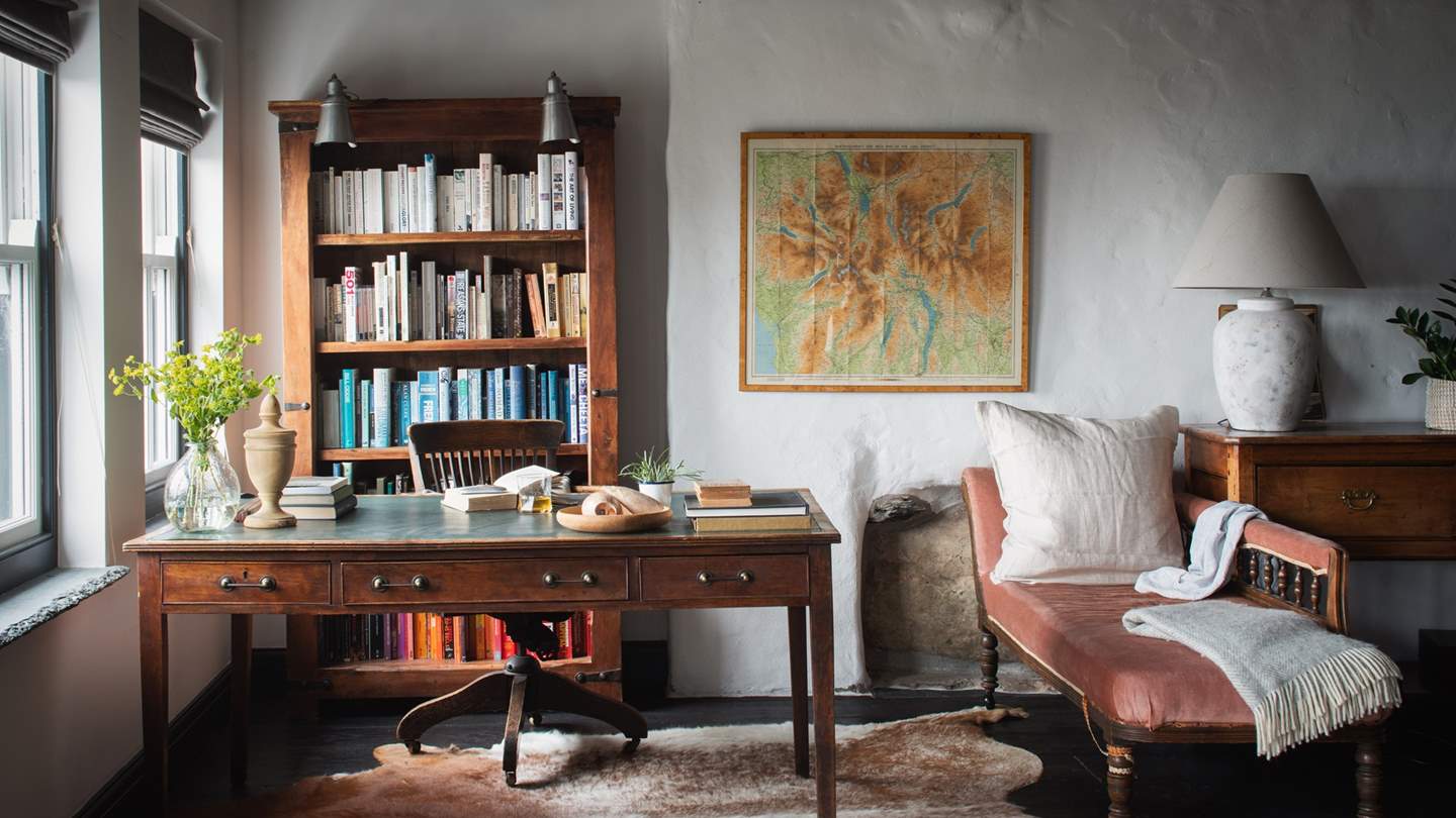 Tucked in the corner and resting on a statement cowhide rug, the chic mid-century writing desk provides both a tranquil work from home space