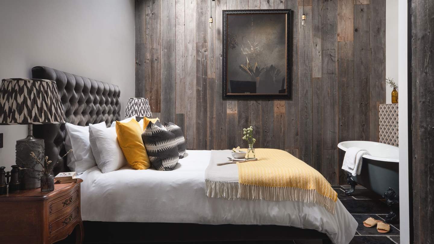 The charming master bedroom is romantic retreats from reality, with inviting charcoal tones and an eye-catching wooden feature wall