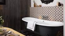 Before the bed, you’ll find a striking jet black rolltop bathtub