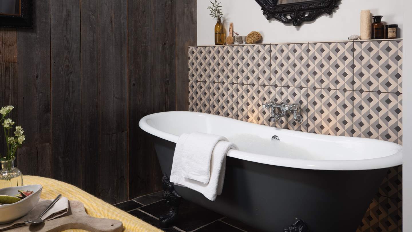 Before the bed, you’ll find a striking jet black rolltop bathtub
