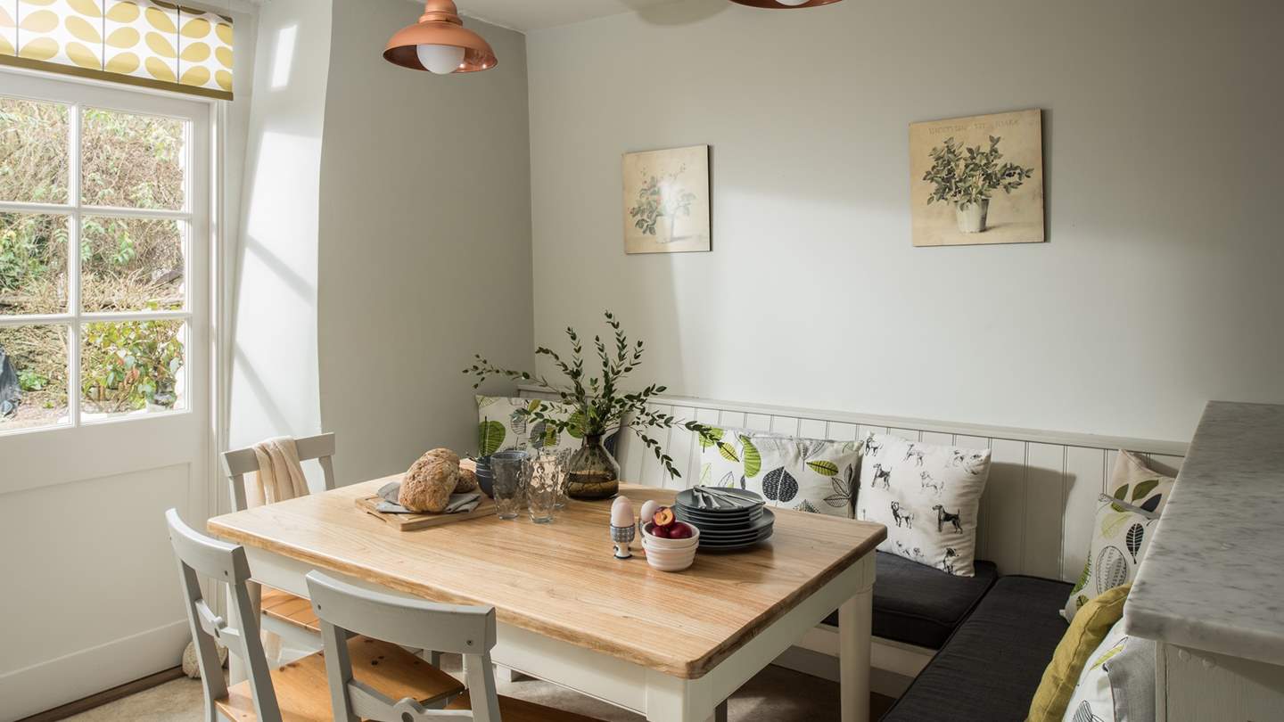 Seating the whole family, a farmhouse kitchen table, chairs and cosy bench with plump cushions completes this space, overlooked by exposed beams and botanical prints