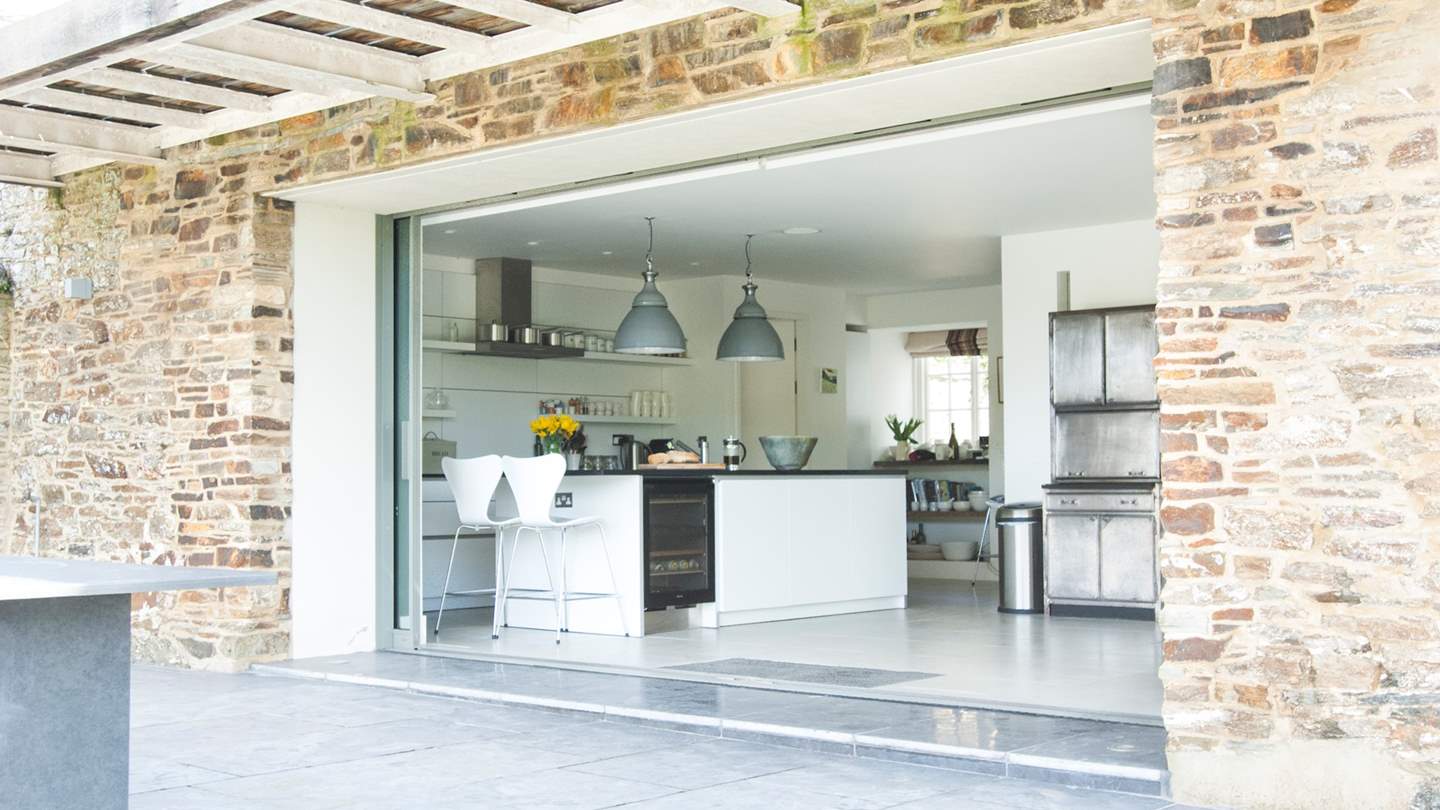 Glass doors disappear into the walls, so the room opens out to the terrace beyond and bespoke slate dining table
