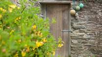 A doorway through an old stone wall into the gardens surrounding The Miller's House
