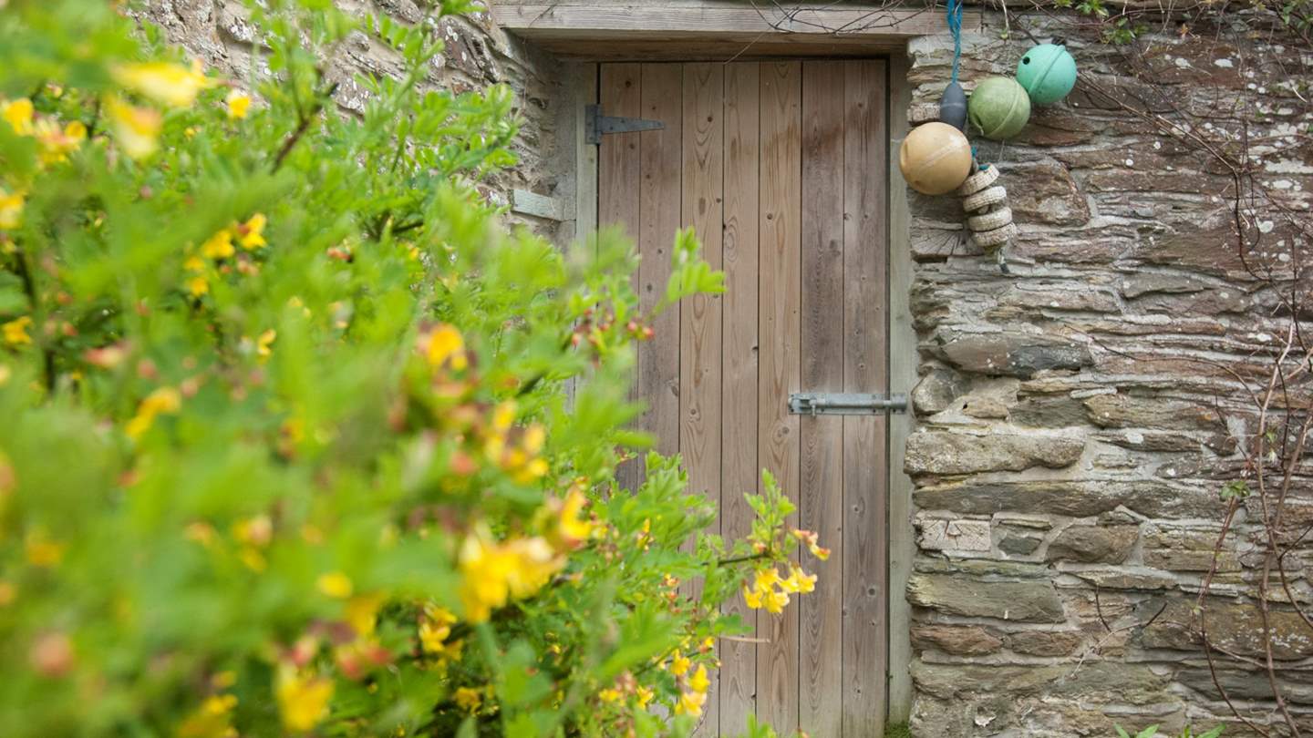 A doorway through an old stone wall into the gardens surrounding The Miller's House