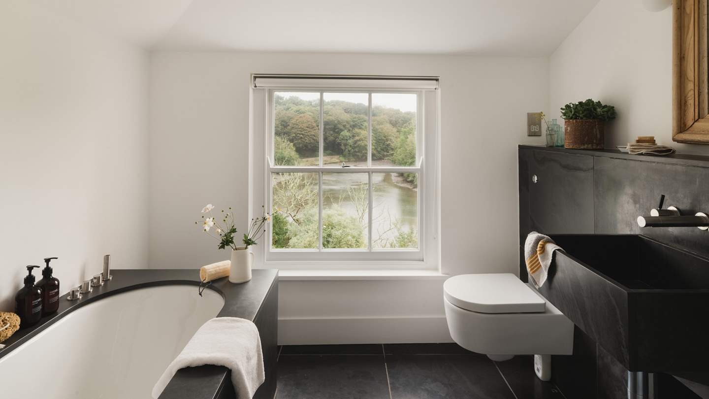 The en suite bathroom with slate basins and a slate sided bath, with a perfectly positioned window to watch the tide ebb and flow in the creek