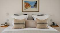 Tranquil tones adorn the second bedroom, where plump cushions and cosy throws embellish the sweet double bed