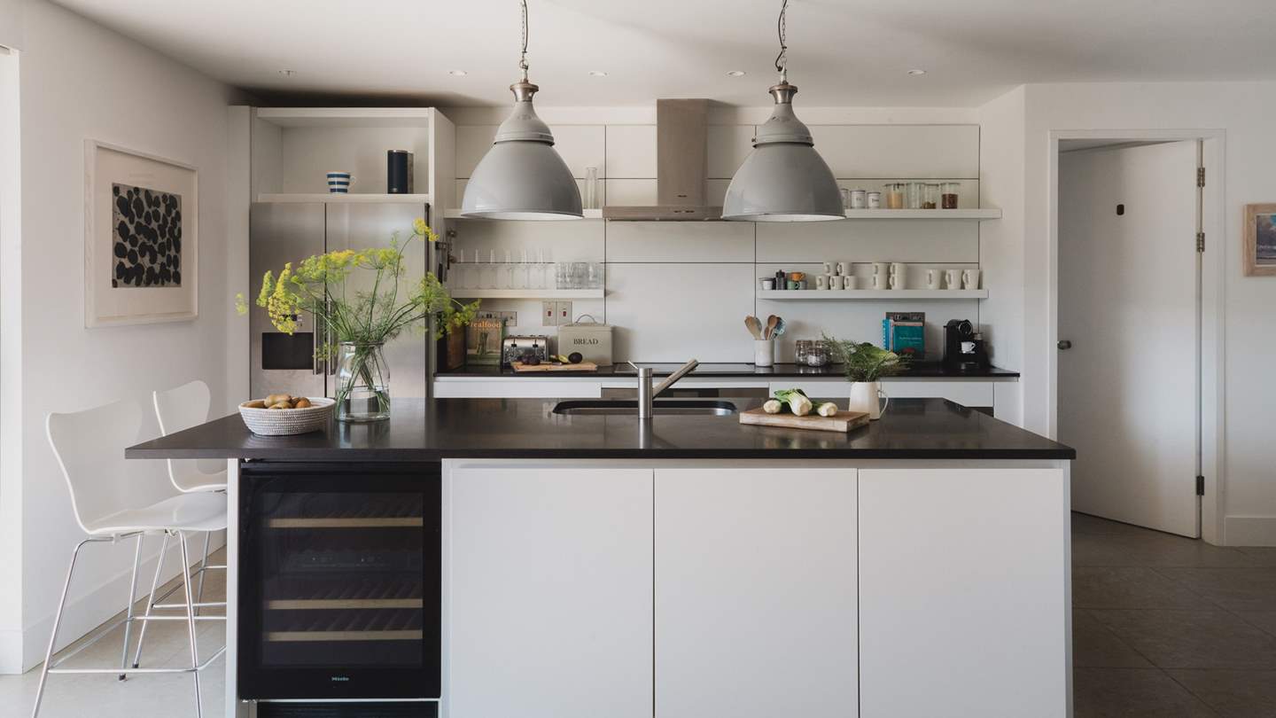 The chic light-filled kitchen has sleek white units, a top-of-the-range steam oven and a island unit, perfect for prepping mealtimes together 