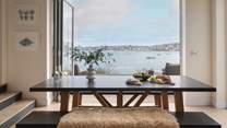 A wooden table with bench seats provides the perfect setting for relaxed dining, with the most magnificent views across the water 