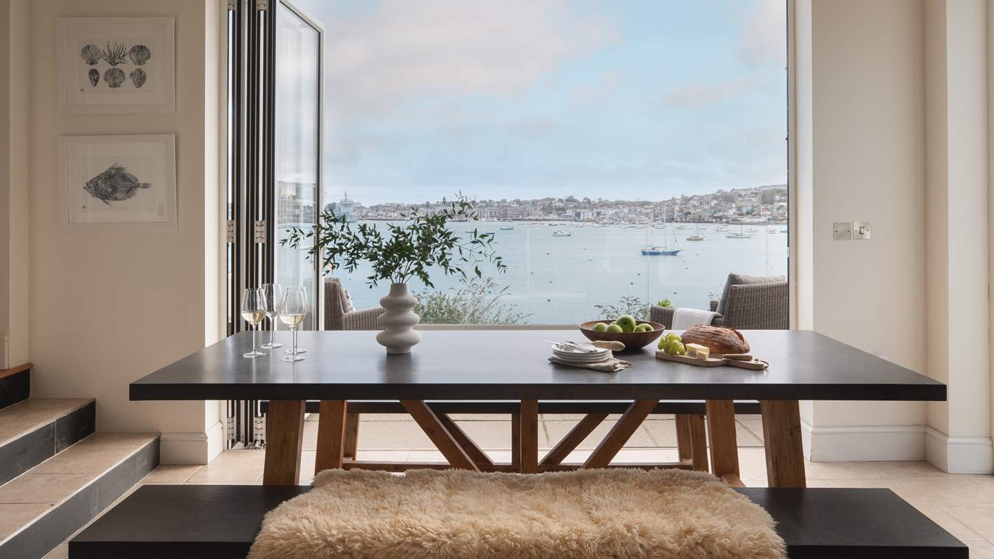 A wooden table with bench seats provides the perfect setting for relaxed dining, with the most magnificent views across the water 