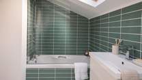 The top floor family bathroom has fetching green tiles and a bath with an overhead shower