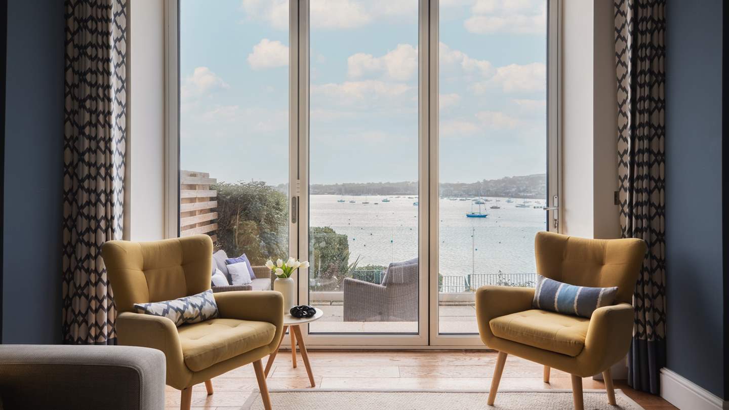 Two comfortable occasional chairs sit besides the glass doors, overlooking sublime ocean vistas