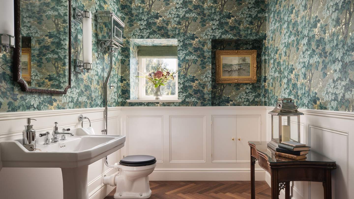 The elegant downstairs toilet is beautifully decorated with William Morris wallpaper