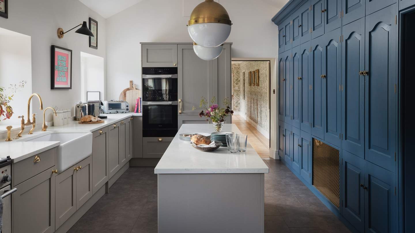 The exquisitely curated kitchen features a bespoke, floor-to-ceiling kitchen storage unit in blue 