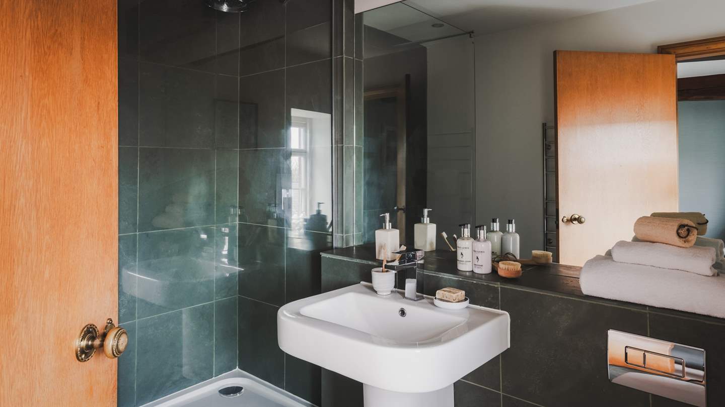 Reflecting Cumbrian forest tones with emerald-coloured tiles, this attractive bathroom has a walk-in shower with a rainfall shower head