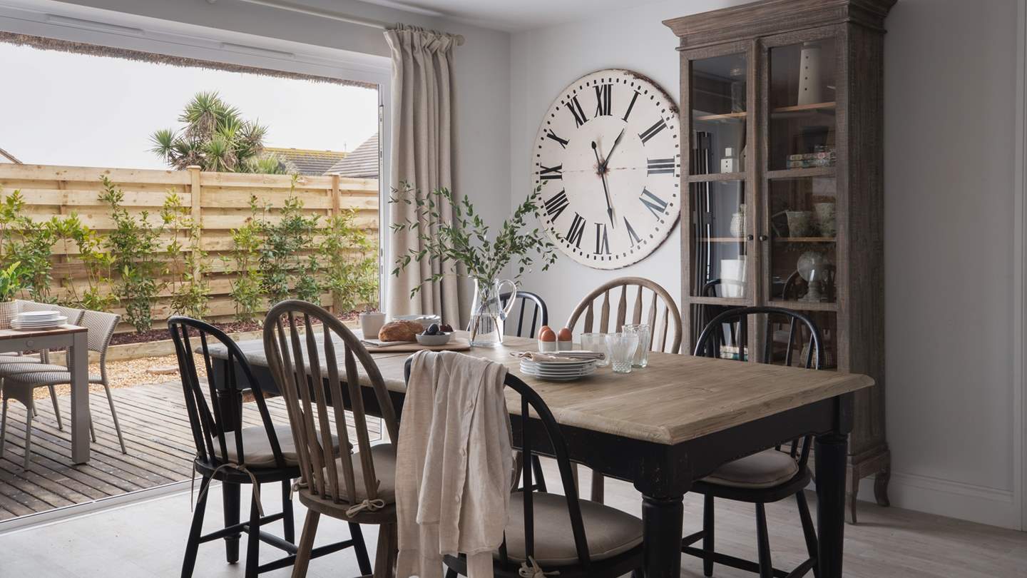 Uncover the open-plan kitchen and dining area, where large glass doors lead towards the decking area
