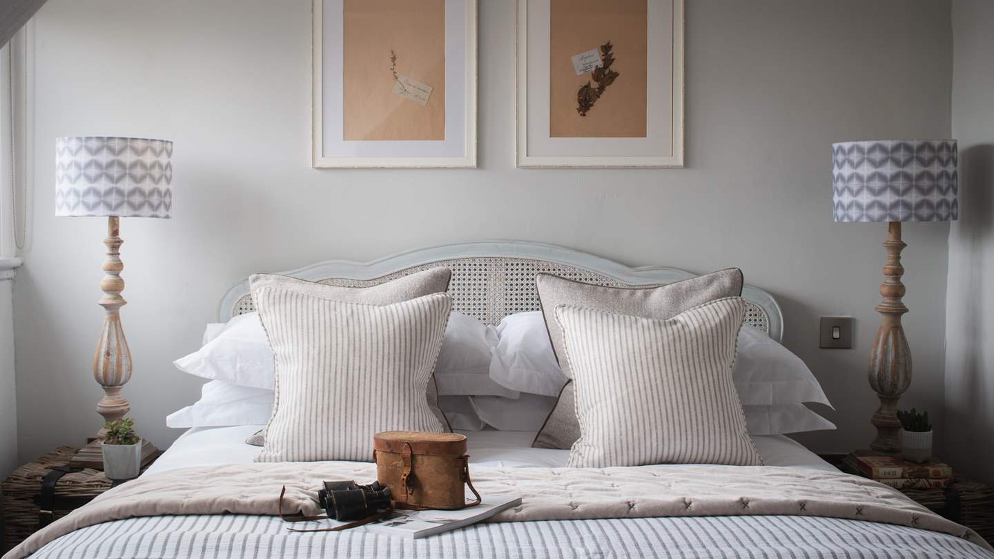 At the foot of the king-sized bed two woven stools await, along with an occasional chair and a Scandi-style chest of drawers
