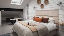 Set under a skylight, a super-king Divan bed, hanging rail, chest of drawers and Roberts radio paint the picture,