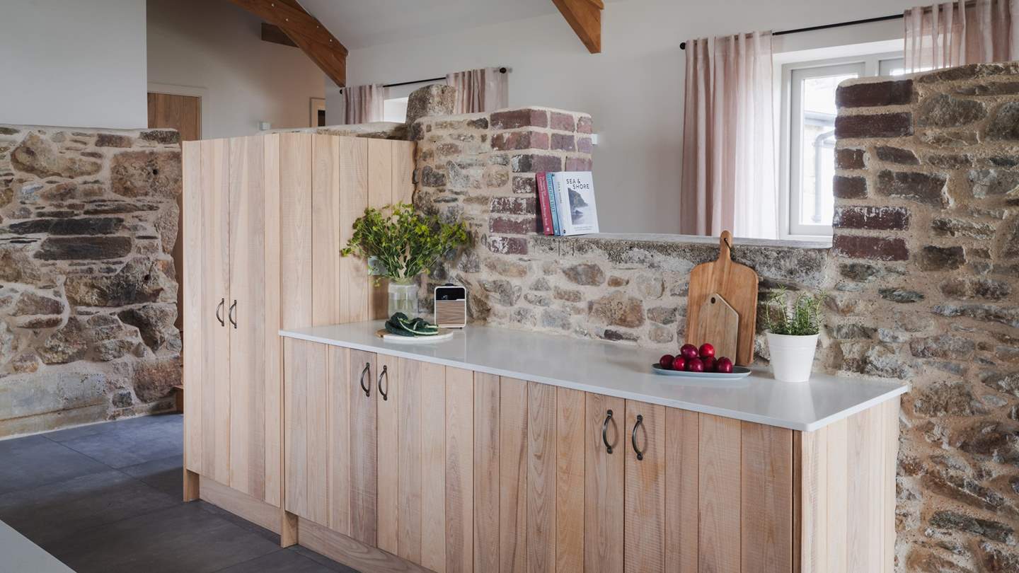 Exposed stone walls interspersed with the sleek white walls and bespoke quartz worktops create a symphony of classic and modern styles