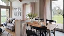 A rustic dining table looks over the living area, with the far-flung rural views beyond offering a peaceful backdrop to your meal