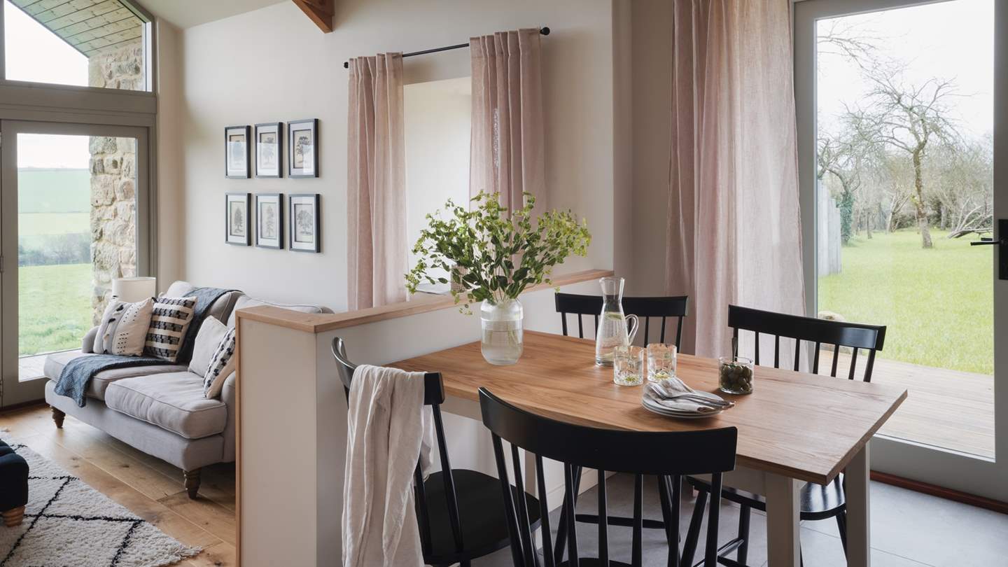 A rustic dining table looks over the living area, with the far-flung rural views beyond offering a peaceful backdrop to your meal