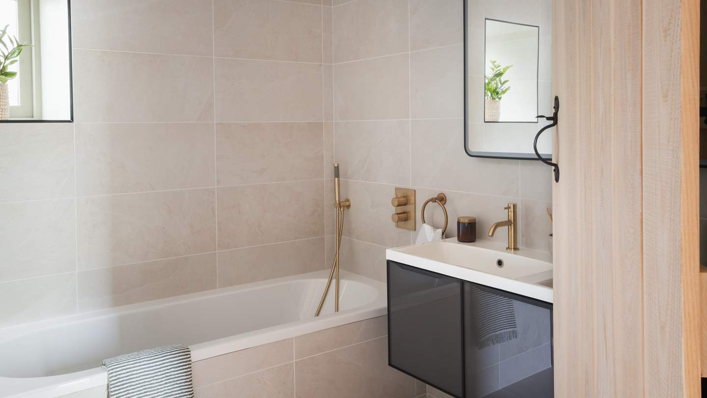 Neutral tones provide a serene atmosphere, with brass fixtures adding a wisp of opulence to the room