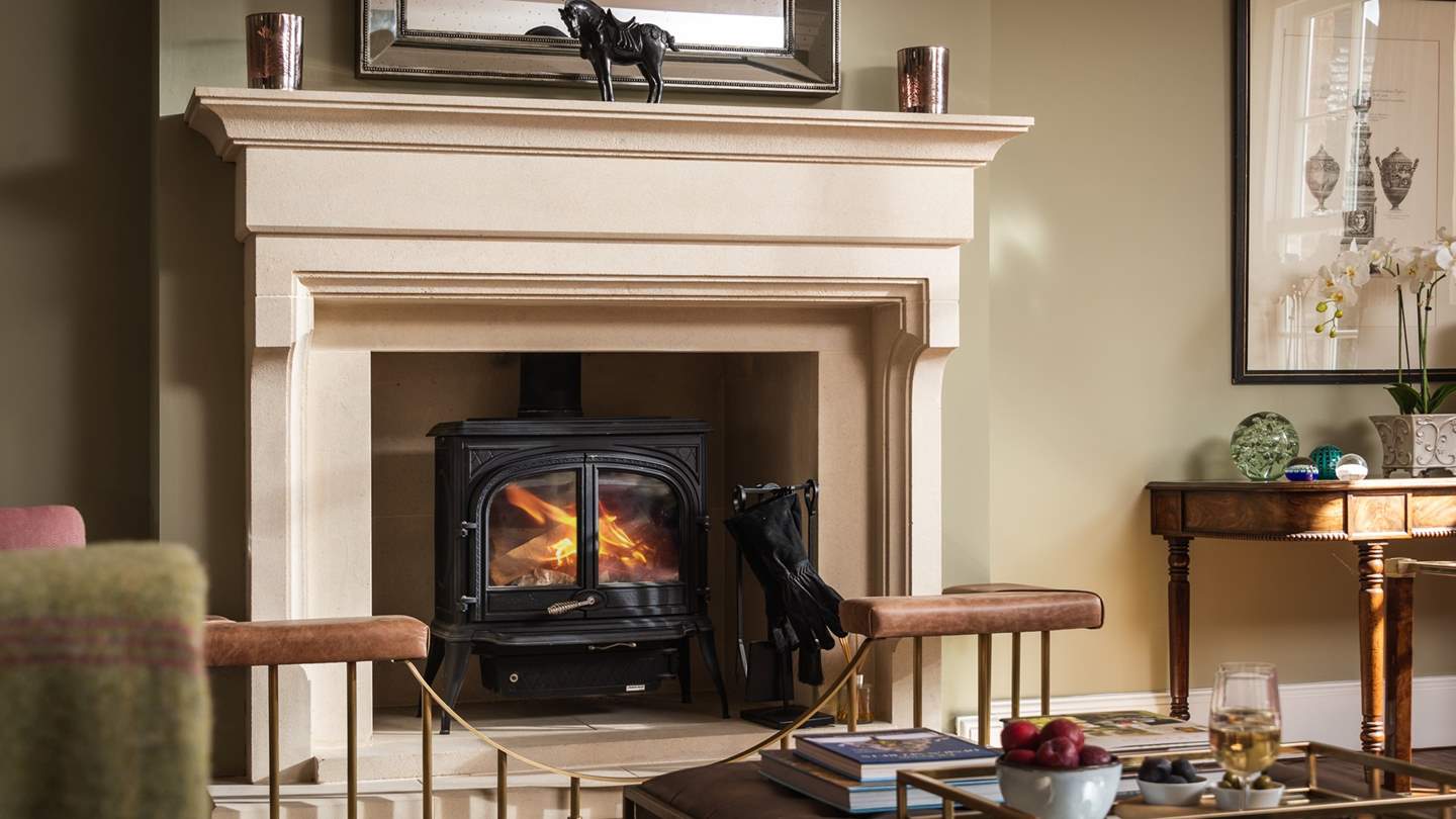 The drawing room with three large sofas and a wood burning stove 