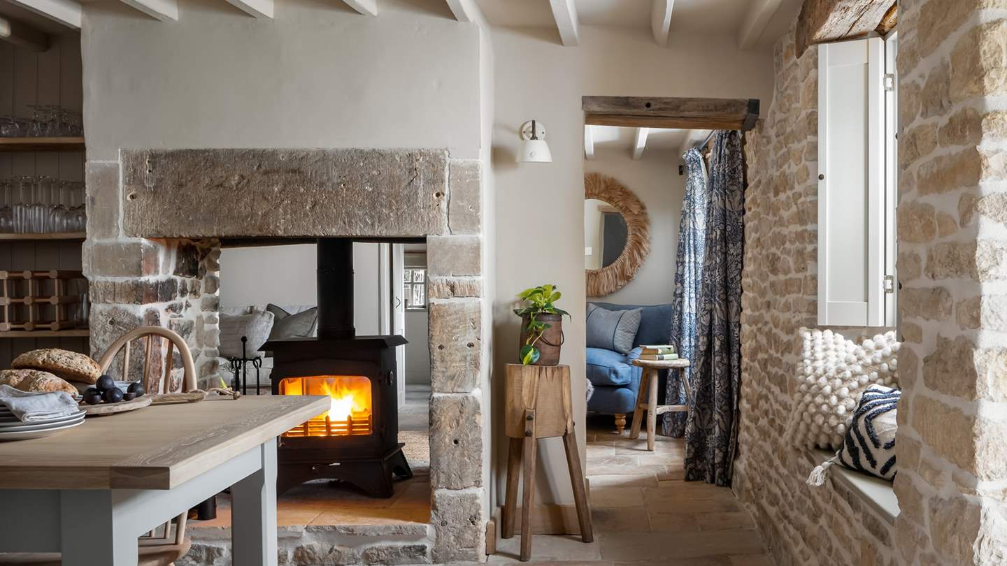 Through the adjoining door is an additional dining area, where an exposed stone, dual sided fireplace separates the living room