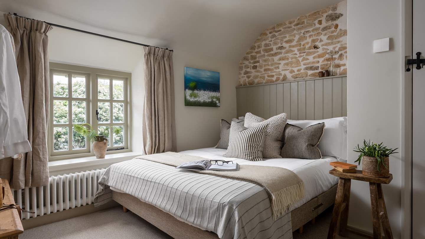 In the third bedroom, an exposed stone feature wall rests above a king-sized bed