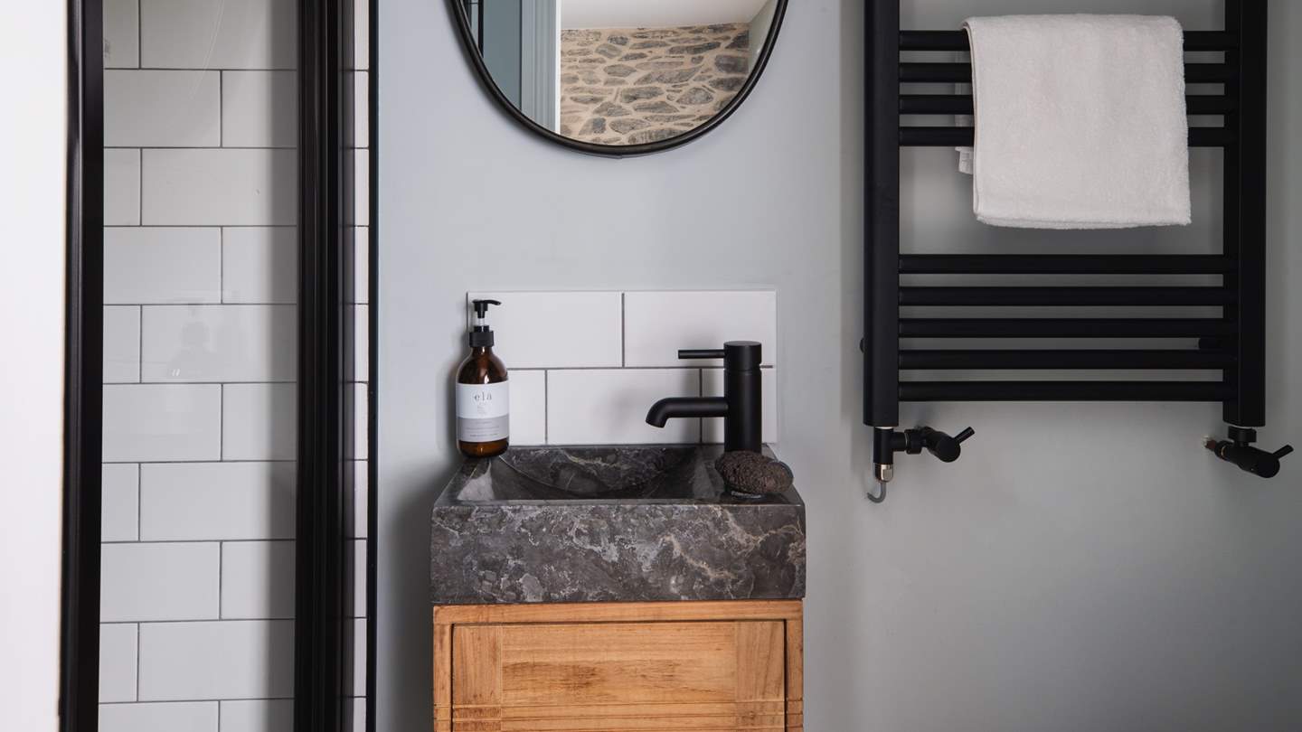This bedroom is complemented by an ensuite shower room where white tiles and black details create tasteful contrast and contemporary style