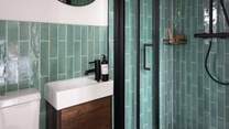A lovely ensuite with attractive turquoise tiles offers a splash of coastal charm