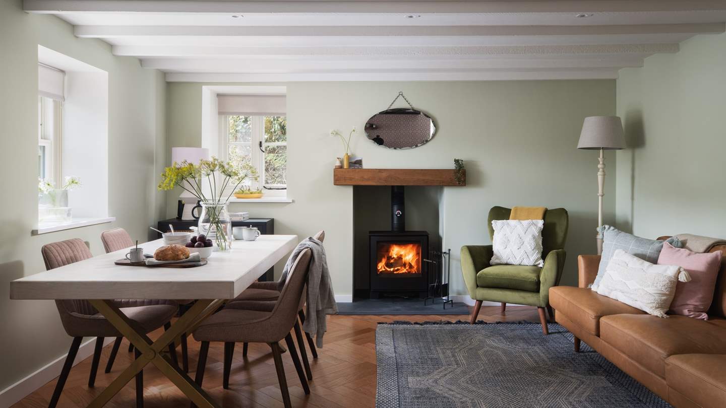 A thoroughly inviting space, the living area features a super cosy West Elm leather sofa and a comfy, olive-green armchair positioned next to a soul-warming wood burning stove