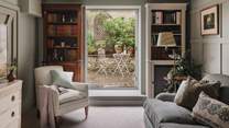 At the far side of the room, French doors open onto the paved patio, welcoming the outside in on balmy summer days