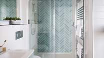 A large shower with teal parquet tiling can be found in the ensuite, with a rainfall shower head for wake-me-up mornings