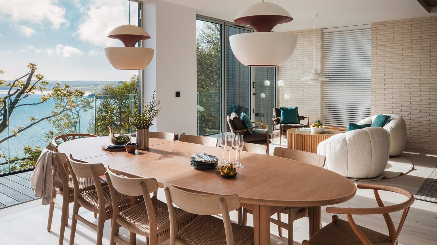 A grand Skovby dining table is positioned in the centre of the room, with original Hans Wegner chairs to seat twelve