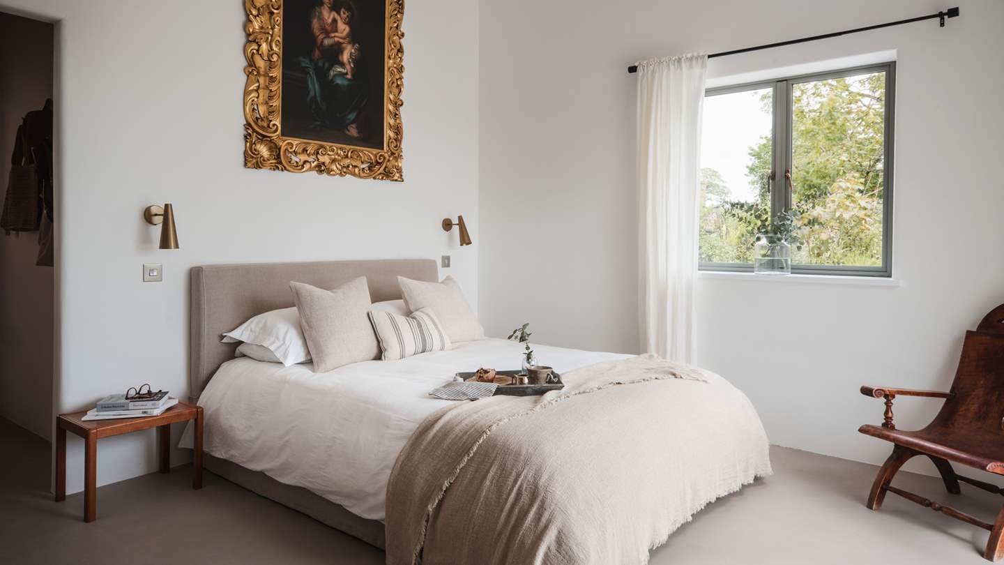 The master bedroom can be found on the ground floor, where a king-sized bed dressed in ecru-toned linens
